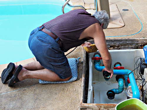 Man cleaning pool pump
